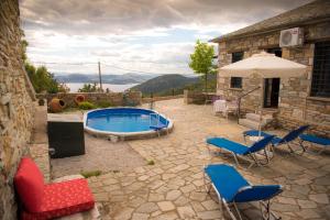 eine Terrasse mit einem Pool, Stühlen und einem Sonnenschirm in der Unterkunft Pelion Goddess Villas in Agios Georgios Nileias