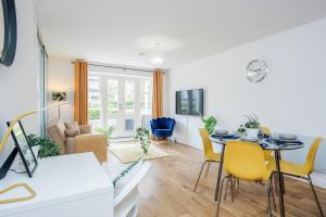 a living room with a dining room table and yellow chairs at King Bed Manhattan Close to London Heathrow in West Drayton