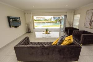 ein Wohnzimmer mit einem braunen Sofa und einem TV in der Unterkunft The Holy Hill Royal Alfred Marina in Port Alfred