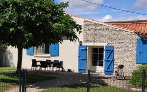 Casa con persianas azules, mesa y sillas en Gîte du Clos de la Vigne, en Montreuil