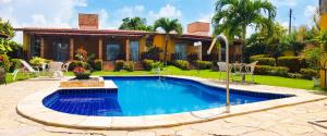 a swimming pool in front of a house at Pousada Aconchego in Pitimbu