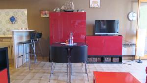 um quarto com uma mesa e uma televisão e armários vermelhos em Sol-y-Days Murènes, Grand studio confortable avec parking, proche du centre ville et de la plage em Le Grau-du-Roi