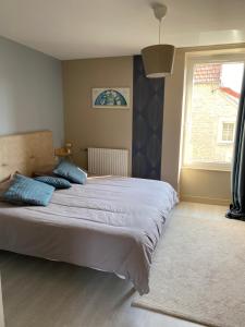 a bedroom with a large bed and a window at Au Rythme des Vagues in Saint-Aubin-sur-Mer