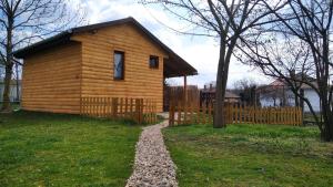 a log cabin with a fence and a gravel path at Csónakház in Tiszadob