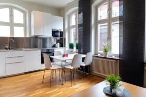 a kitchen with white cabinets and a table and chairs at City HotelApartment in Karlshamn