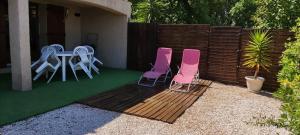 eine Terrasse mit 2 Stühlen, einem Tisch und einem Zaun in der Unterkunft Studio L'agasso Prouvenco in La Crau