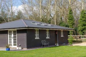 a small black house with a chair in a yard at Breckland Cottage - Secluded Country Getaway in Hockwold cum Wilton