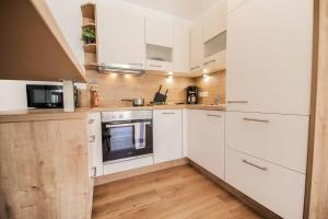 una cucina con elettrodomestici bianchi e pavimenti in legno di Ferienwohnung Alpenland - schönes, neues Apartment a Neustift im Stubaital