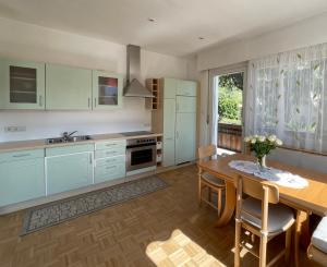 a kitchen with white cabinets and a wooden table at Naif-Home in Merano +6 photos