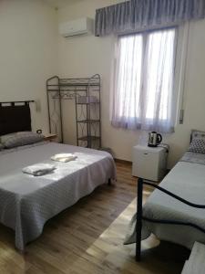 een slaapkamer met 2 bedden en een raam bij B&B Casa Delfina in Capoterra