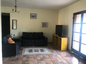 a living room with a black couch and a tv at CHÁCARA GODOI - Meu Paraíso in Itu