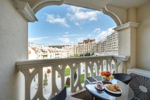 瓦爾納的住宿－Summertime in Varna South Bay Beach Residence，阳台配有带食品的桌子,享有建筑的景致。