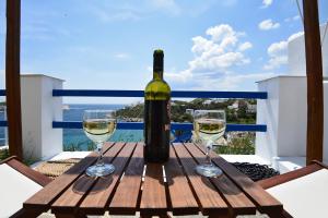 una botella de vino sentada en una mesa con dos copas en Deck2 Syros Premium Apartments, en Vári