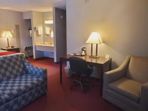 a hotel room with a desk and chairs and a bed at Blackstone Lodge and Suites in Lead