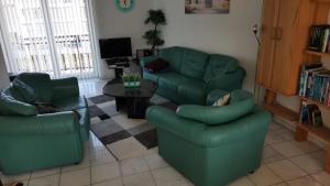 Una sala de estar con un sofá verde y sillas. en Marina 68/70, en Cuxhaven