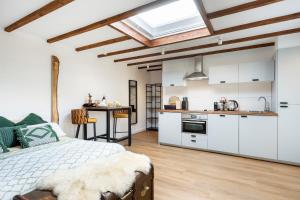 een slaapkamer met een bed en een keuken met witte kasten bij Cottage 44 - Free parking! in Zandvoort