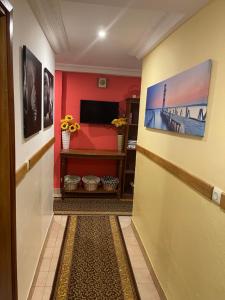 a hallway with a red wall with a painting on the wall at Homestay Appartement 2 chambres in Yaoundé