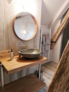 uma casa de banho com um lavatório de pedra e um espelho. em Tuilerie de Talouan Maison de maître 4 étoiles écologique et tout confort em Villeneuve-sur-Yonne