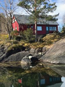 ein rotes Haus auf einem Hügel neben dem Wasser in der Unterkunft Teigen Leirstad, feriehus og hytter in Eikefjord