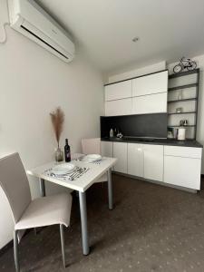 a white kitchen with a white table and chairs at Apartments & Rooms Villa Zaad FREE PRIVATE PARKING in Mostar