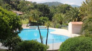 a swimming pool with a fence and palm trees at Favone Mini Villa Playa del Oro in Favone