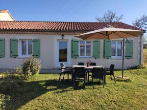 una mesa con sombrilla frente a una casa en La Ferme Des Vergnes en Gabillou