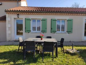 una mesa y sillas frente a una casa en La Ferme Des Vergnes, en Gabillou