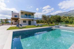 a villa with a swimming pool in front of a house at Terra Divina Villa in Plakias