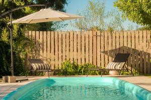 a swimming pool with two chairs and an umbrella at Botanico in Villa Elisa