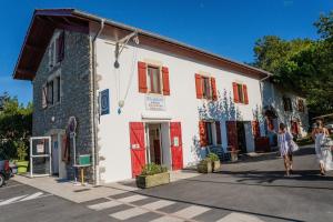 due persone in piedi fuori da un edificio bianco con porte rosse di Camping Harrobia a Bidart