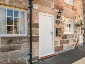 a brick house with a white door and a clock at Stoney Cottage in Saltburn-by-the-Sea
