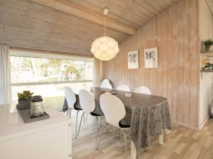 ブロックフスにある6 person holiday home in Blokhusのダイニングルーム(黒いテーブル、白い椅子付)