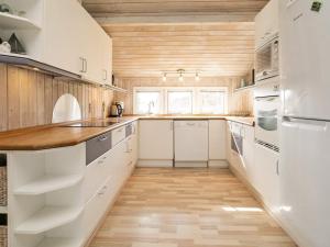 cocina con armarios blancos y techo de madera en 6 person holiday home in Blokhus, en Blokhus