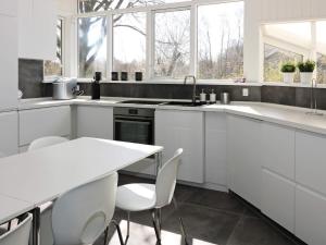 OddeにあるFour-Bedroom Holiday home in Hadsund 4の白いキャビネット、テーブルと椅子付きのキッチンが備わります。