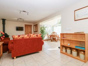 a living room with a red couch and a table at Mynheer Farm Bowji in Redruth