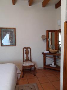 a bedroom with a bed and a chair and a mirror at Casa d'Lobo Hotel Boutique in Malinalco