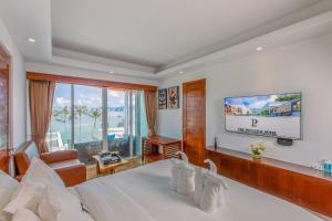 a hotel room with a bed and a tv at The Privilege Hotel Ezra Beach Club in Bang Rak Beach