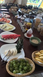 une table avec des assiettes de denrées alimentaires et des fruits et légumes dans l'établissement Pousada Vista Dell Mar, à Ubatuba