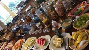 una mesa cubierta con platos de comida y cestas de fruta en Pousada Vista Dell Mar, en Ubatuba