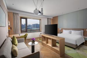 Una habitación de hotel con una cama y un televisor. en Holiday Inn Zhengzhou High-Tech Zone by IHG, en Zhengzhou