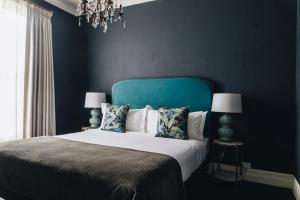 a bedroom with a bed with blue walls and a chandelier at Berida Hotel in Bowral