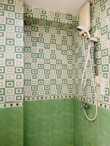 a shower in a bathroom with green and white tiles at Apartemen Cibubur Village by Raja Sulaiman Property in Cibubur