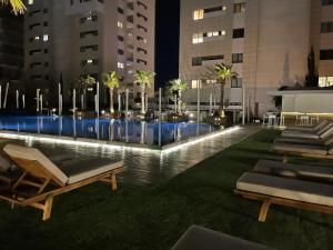 a pool in a city at night with lounge chairs at Olympic Residence Deluxe Apartments in Limassol