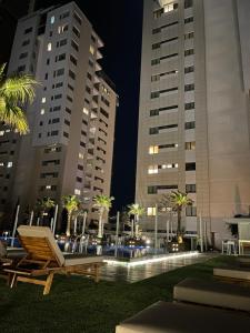 a chaise lounger in a park at night with tall buildings at Olympic Residence Deluxe Apartments in Limassol