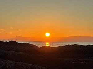 a sunset over the ocean with mountains in the background at Loch Morar Private Suite in Mallaig