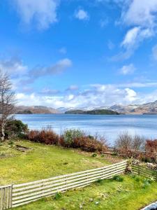 a fence next to a lake with mountains in the background at Loch Morar Private Suite in Mallaig