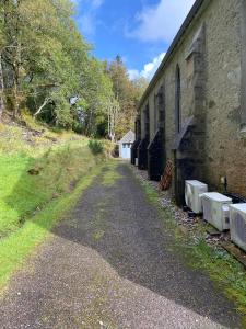 a dirt road next to a brick building at Loch Morar Private Suite in Mallaig