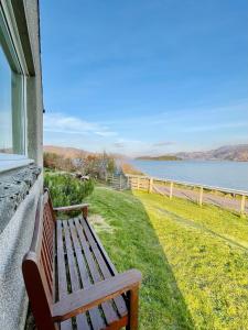 a wooden bench sitting on the side of a house at Loch Morar Private Suite in Mallaig