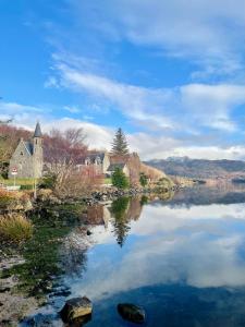 a reflection of a church in the water of a lake at Loch Morar Private Suite in Mallaig