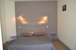 a bedroom with a large bed with two purple tables at Hostellerie De La Poste in Clamecy
